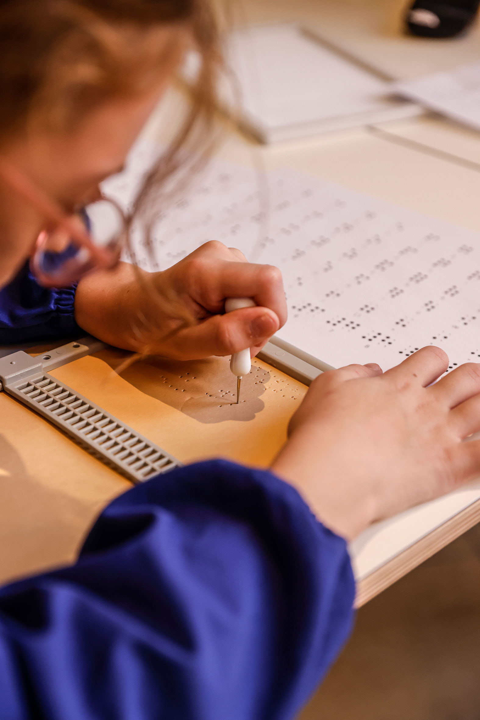 Una bambina intenta ad utilizzare una tavoletta ed un punteruolo per la scrittura Braille