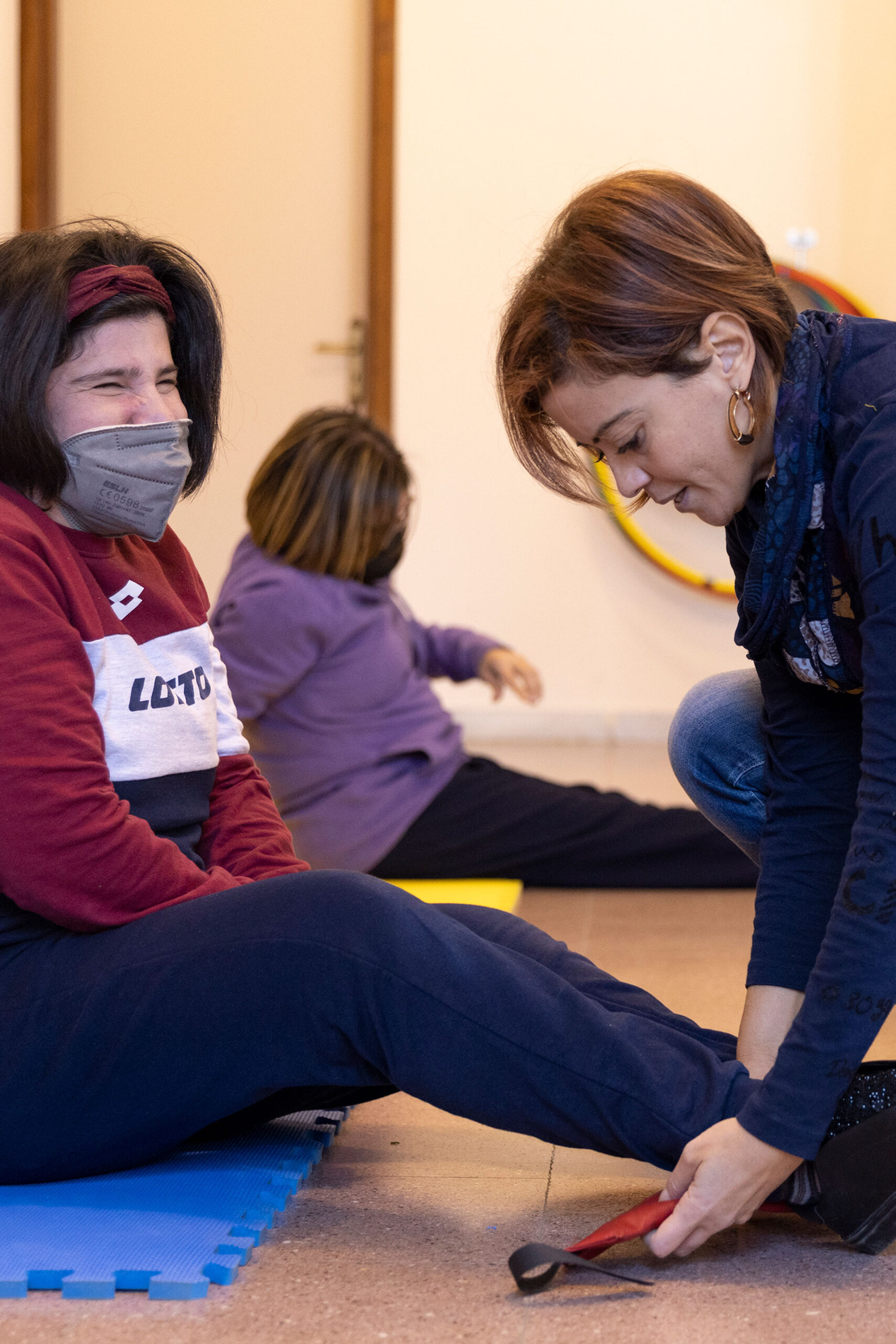 Un'educatrice aiuta un utente a prepararsi per un'attività di ginnastica